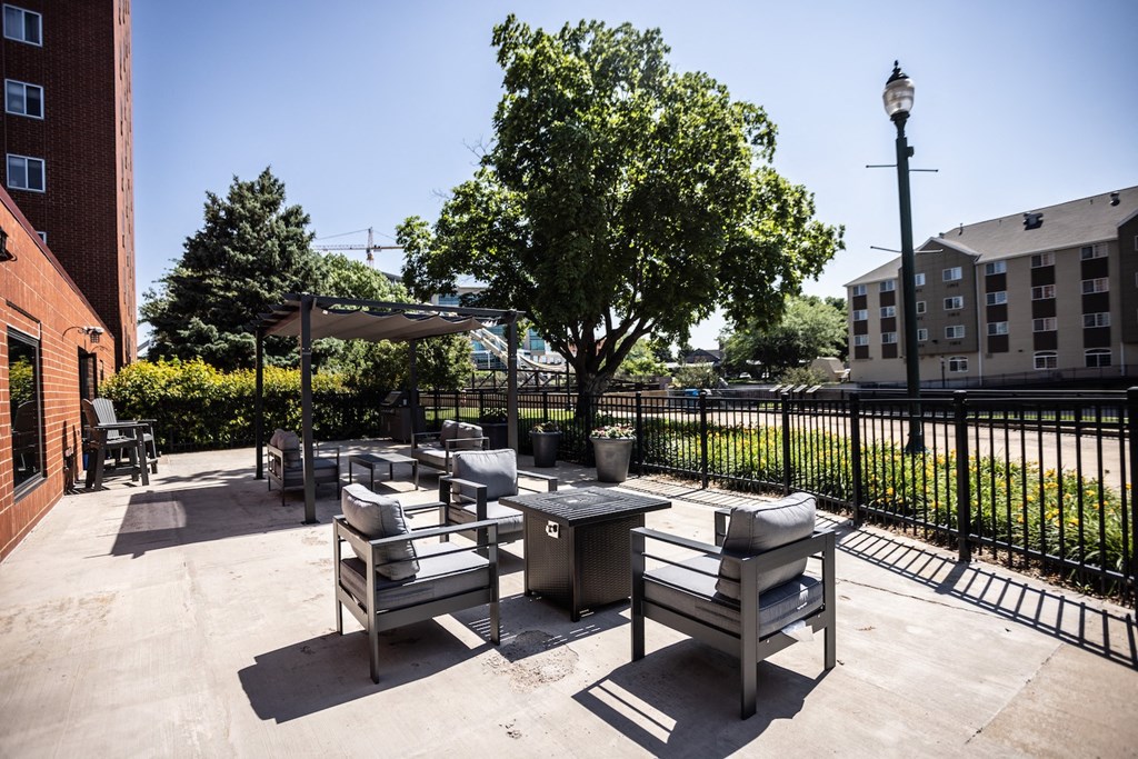 an outdoor patio with tables and chairs and a black fence