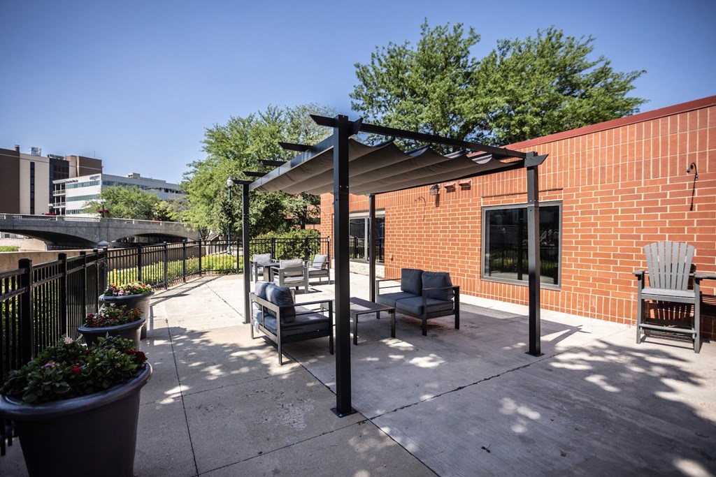 a patio with chairs and a pergola on a sidewalk