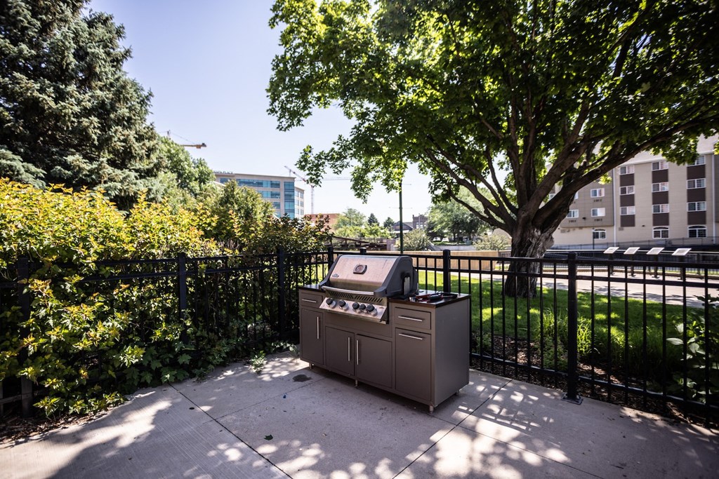 a barbecue grill on a sidewalk next to a fence