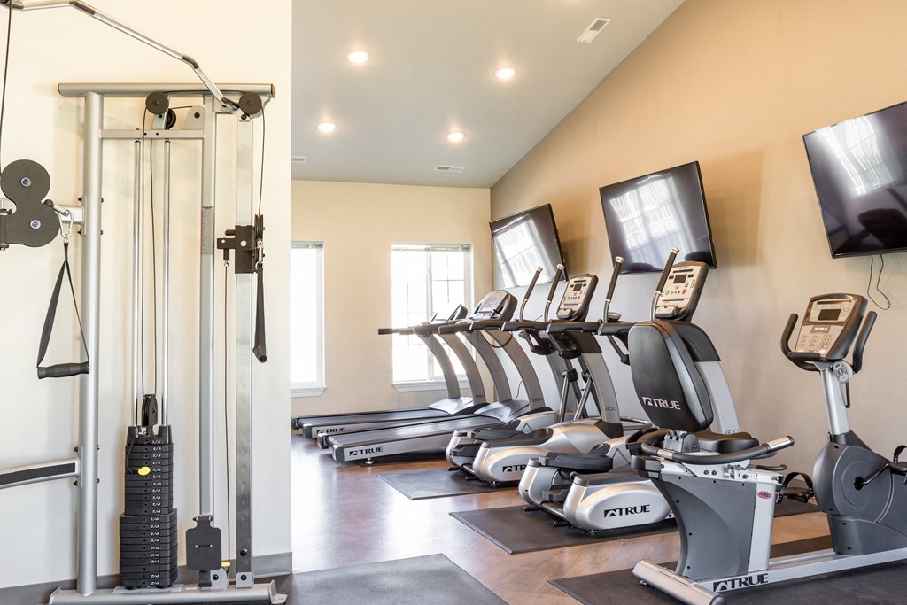 a row of treadmills and televisions in a gym