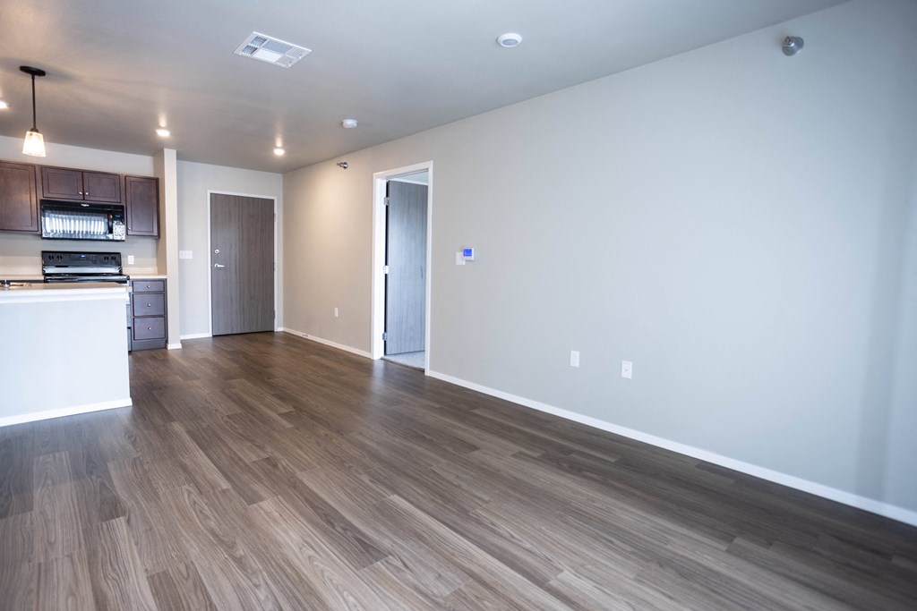 an empty living room and kitchen with wood flooring