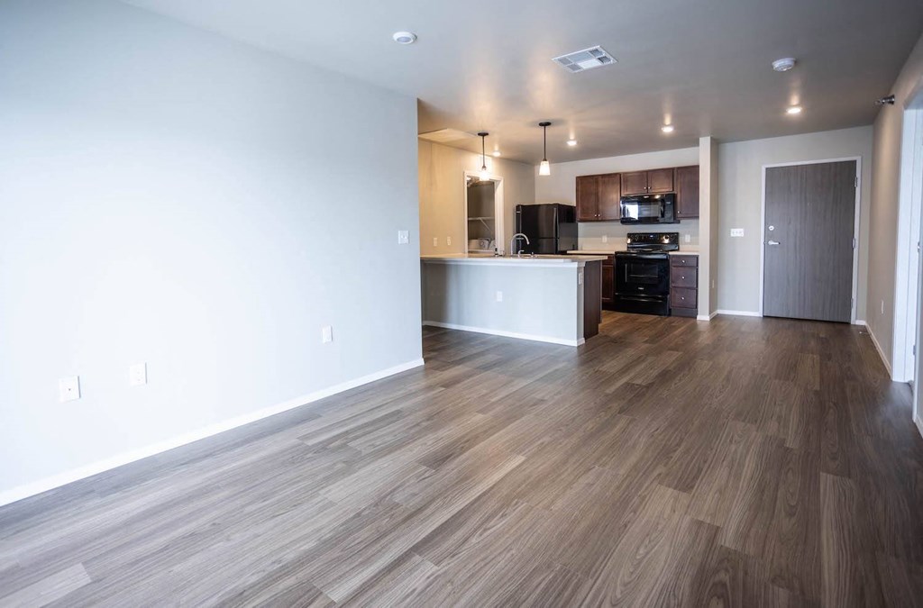 an empty living room and kitchen with wood flooring
