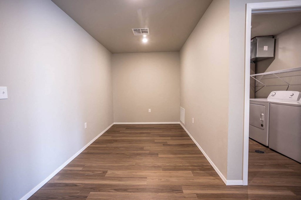 a room with white walls and wood flooring and a laundry room