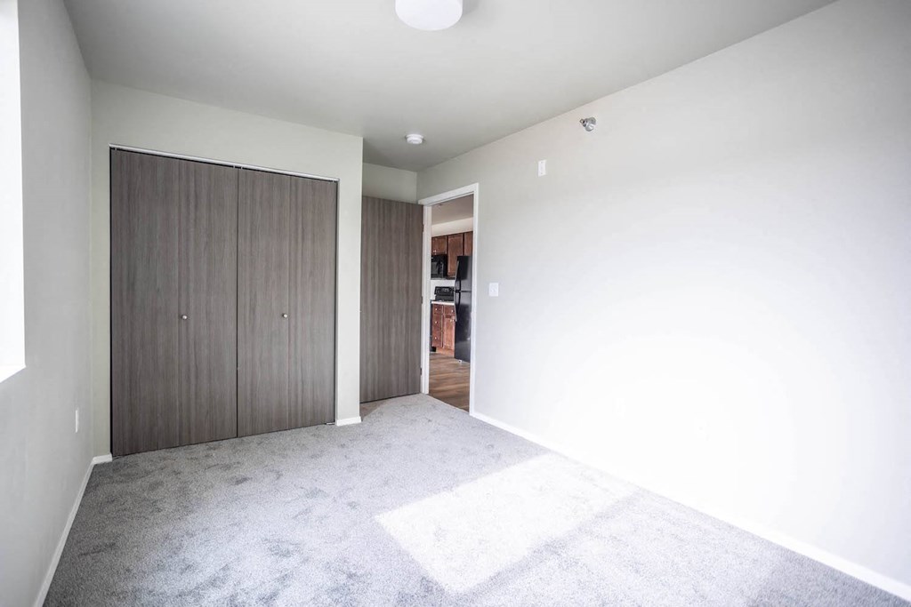 a large empty room with white walls and a wooden closet