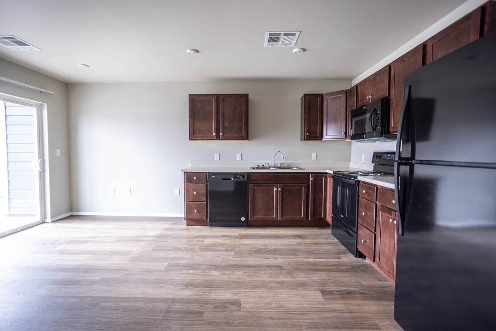 an empty kitchen with wooden floors and black appliances