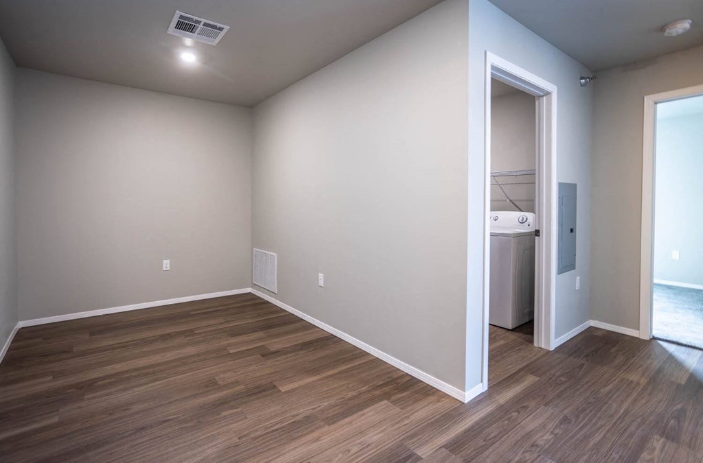 a living room with wood flooring and a door to a laundry room