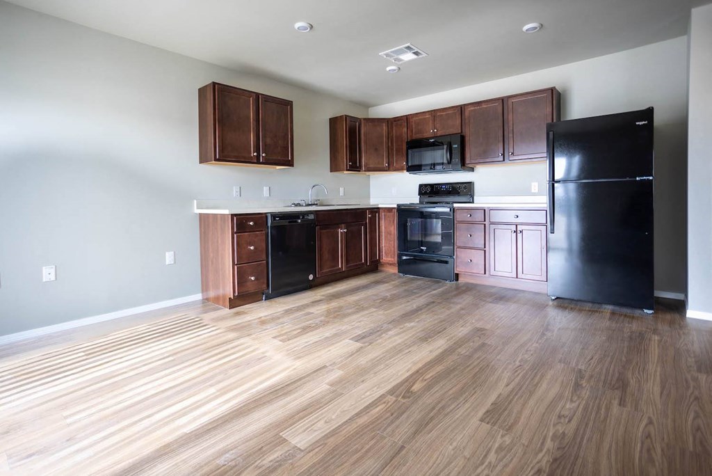 an empty kitchen with wood floors and black appliances