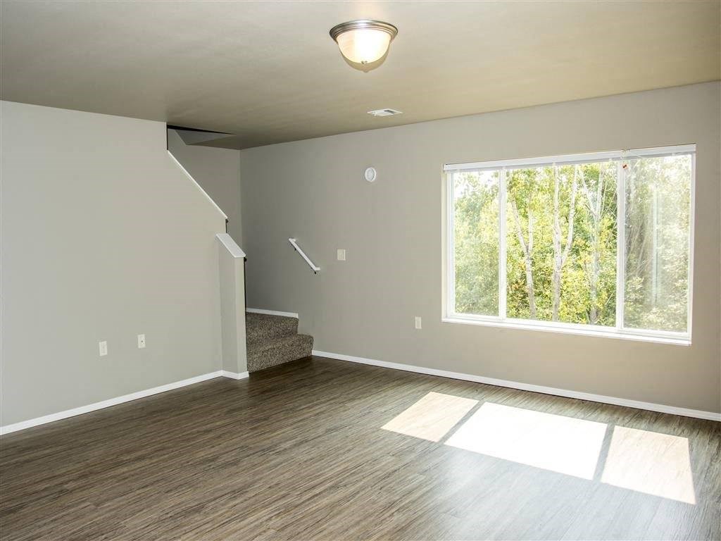 an empty living room with a large window and wooden floors