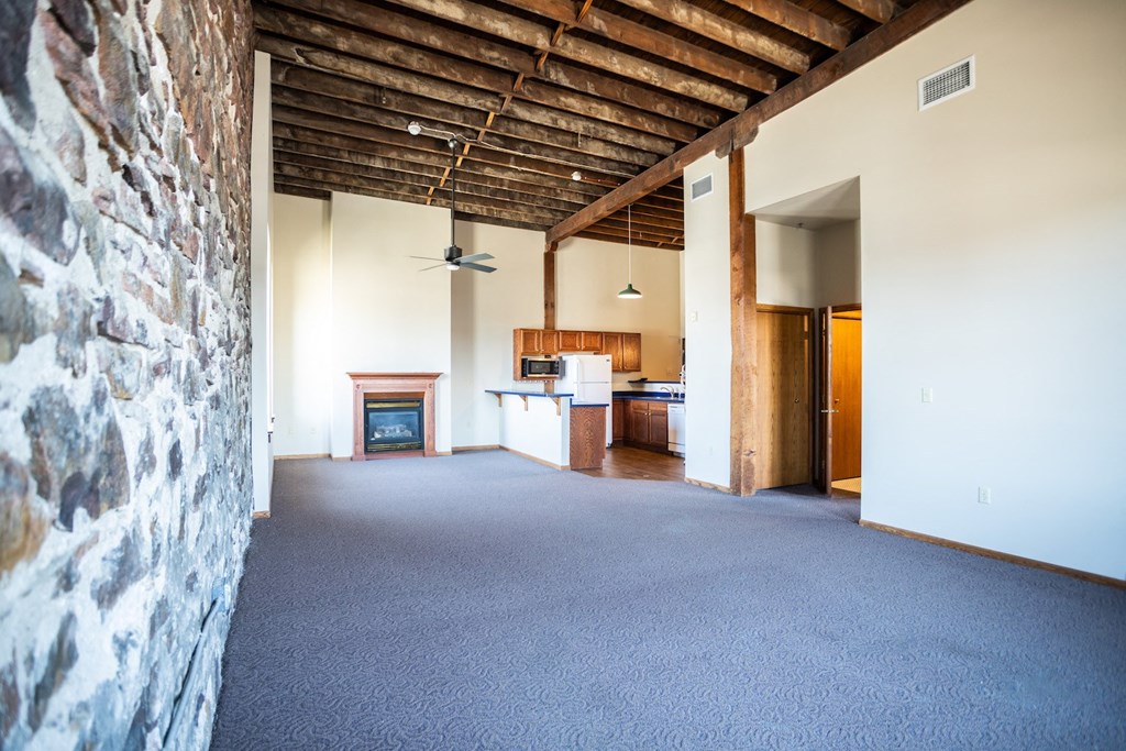 an empty living room with a fireplace and a kitchen