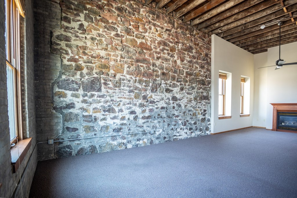 an exposed brick wall in a room with carpet and windows