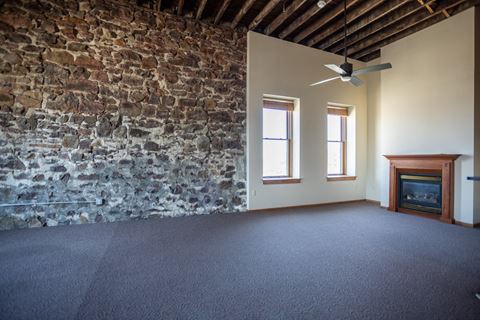 an empty living room with an exposed brick wall
