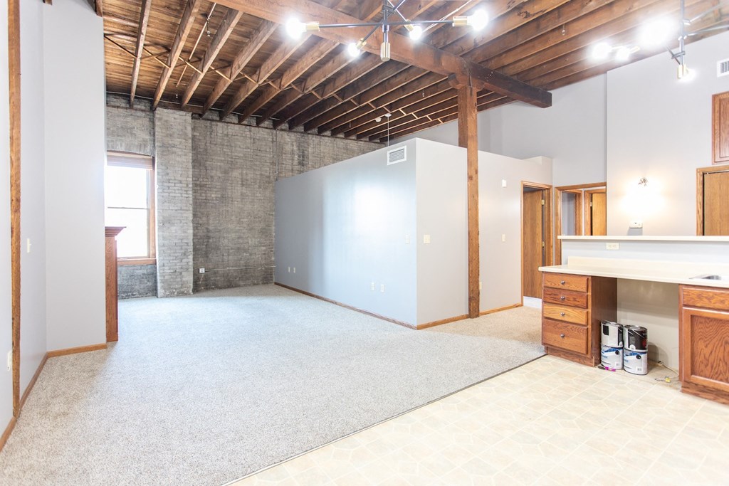 an empty living room with a kitchen and a blue wall
