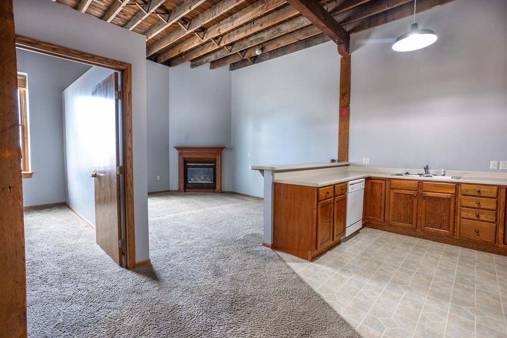 an empty room with a kitchen and a fireplace