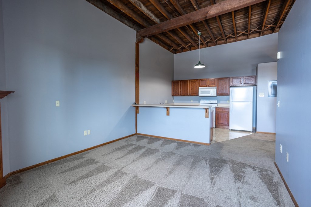 an empty living room and kitchen with a refrigerator and a sink