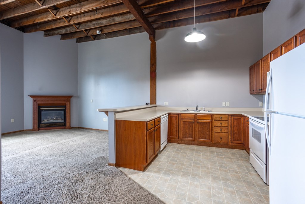 an empty kitchen with wooden cabinets and a fireplace