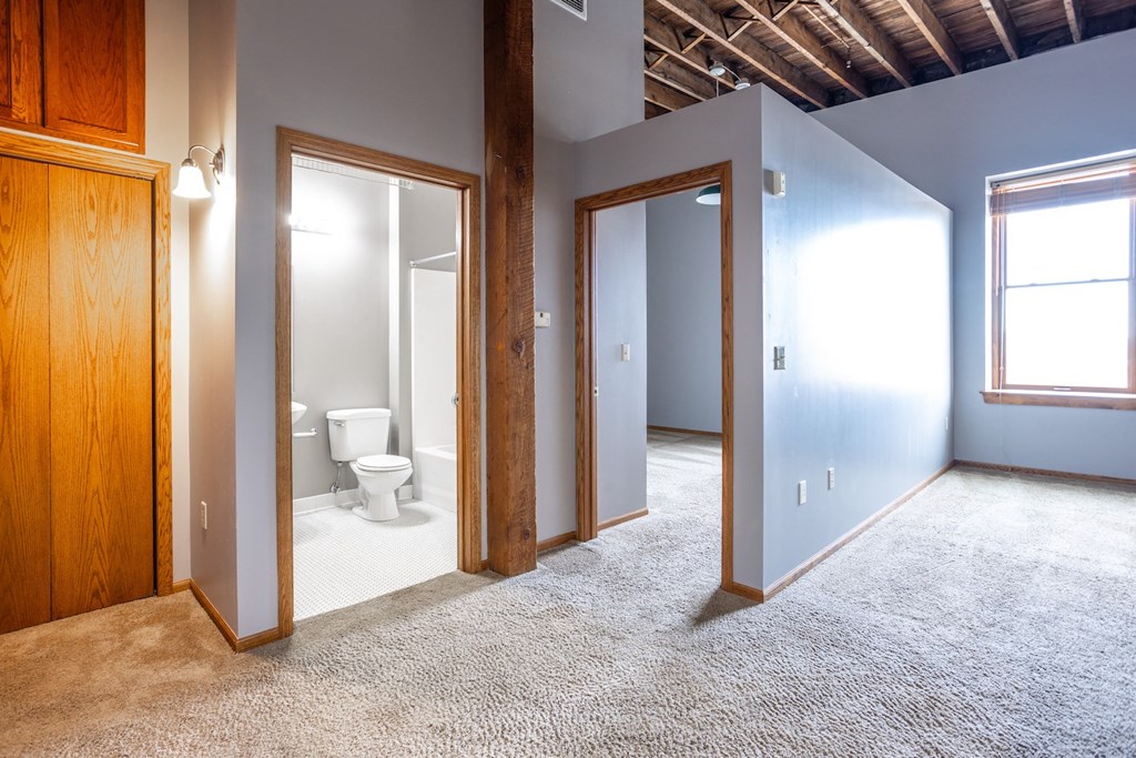 an empty room with a toilet and three doors