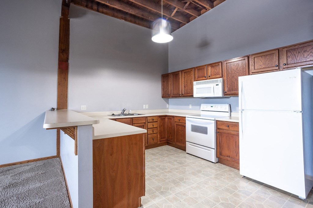 an empty kitchen with white appliances and wooden cabinets