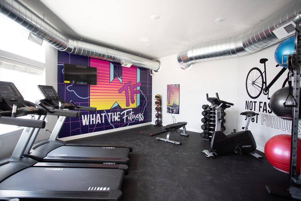 a gym with cardio equipment and a wall mural of what the cross