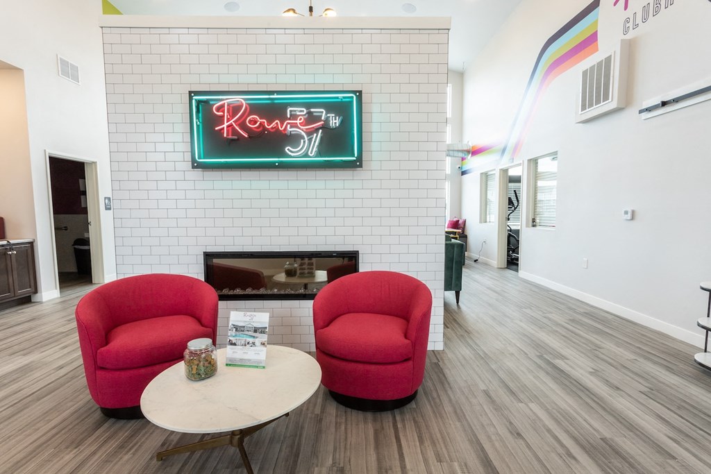a living room with two red chairs and a fireplace