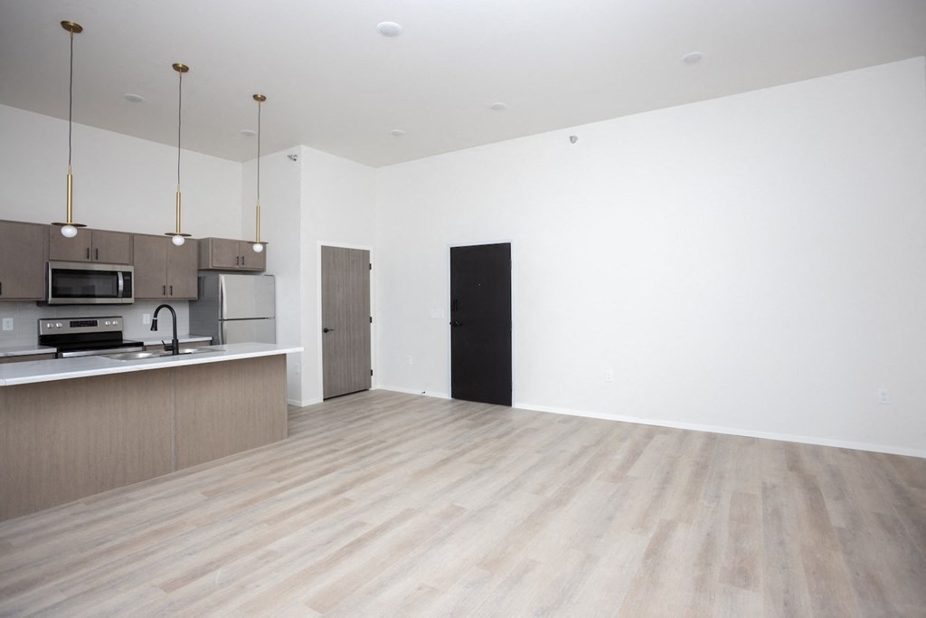 an empty living room and kitchen with white walls and wood floors
