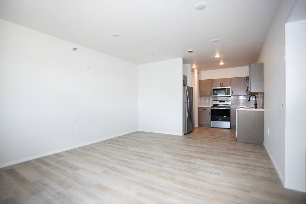 an empty living room with a kitchen in it