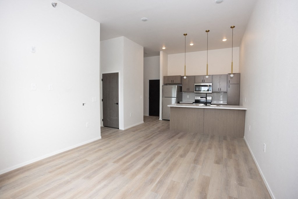 an empty living room and kitchen with white walls and wood floors