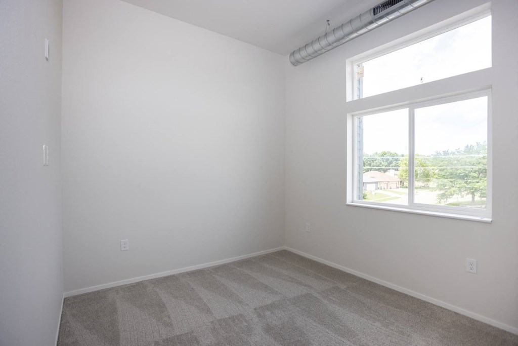 an empty room with a window and carpet