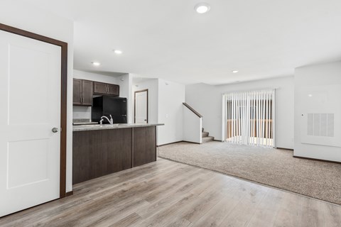 A modern kitchen with a white door and wooden flooring.