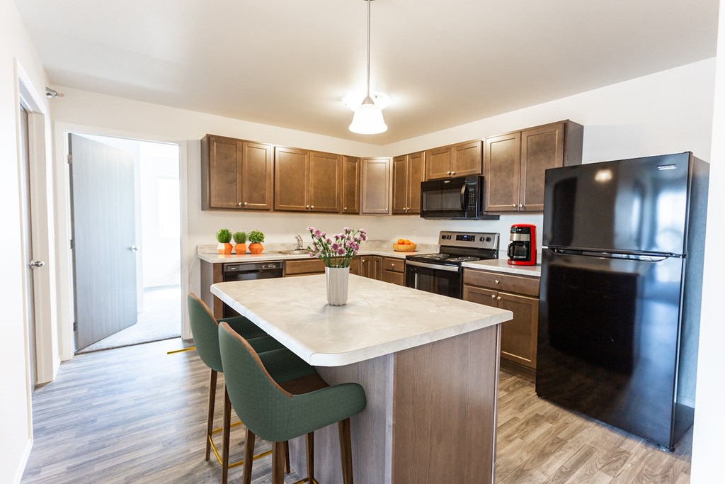 A kitchen with a black refrigerator and a white island.