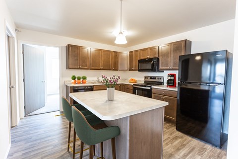 A kitchen with a black refrigerator and a white island.