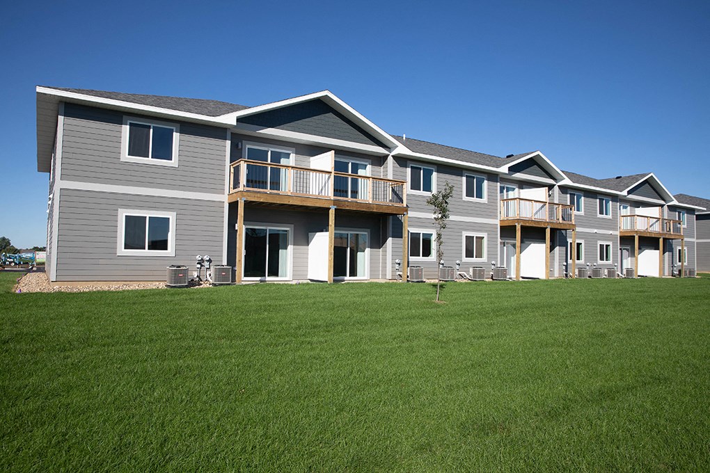 a row of houses with balconies and green grass