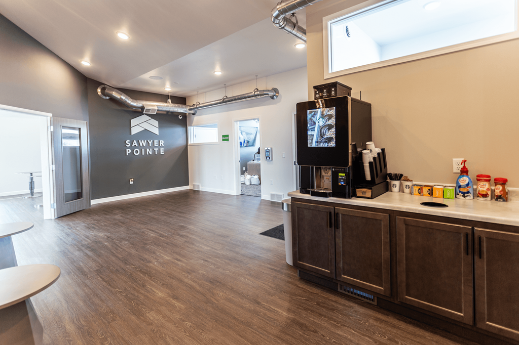 a community room with a coffee bar and a sink in front of a window