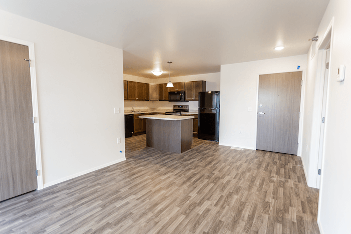 an empty living room and kitchen with a wood floor