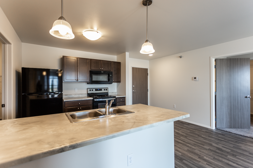 A kitchen with a black refrigerator and a wooden counter top.