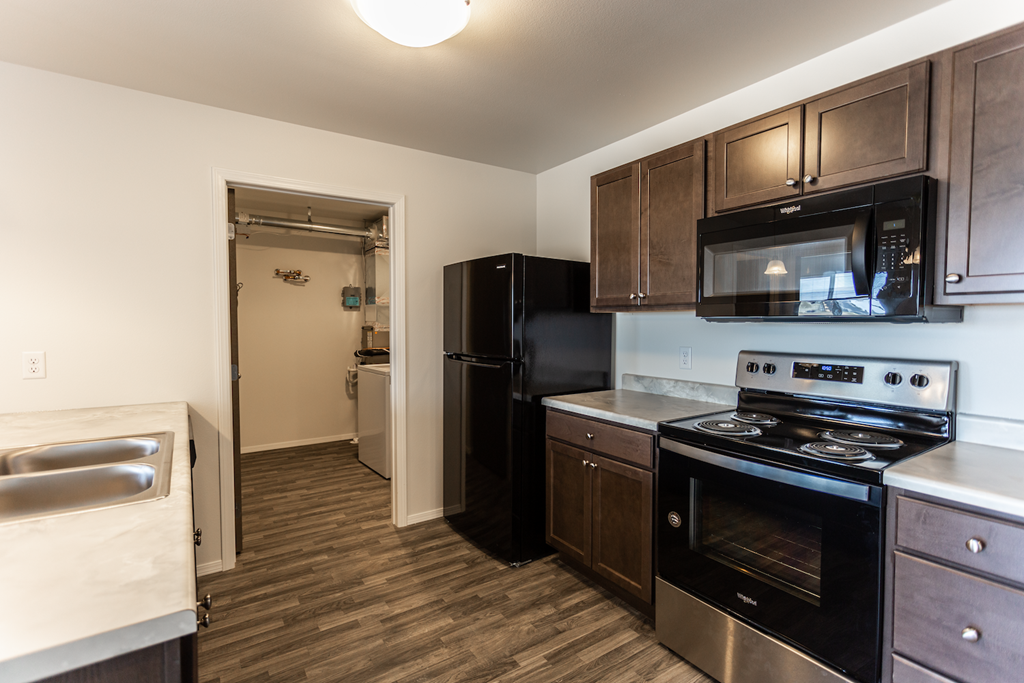 A kitchen with black appliances and wooden cabinets.