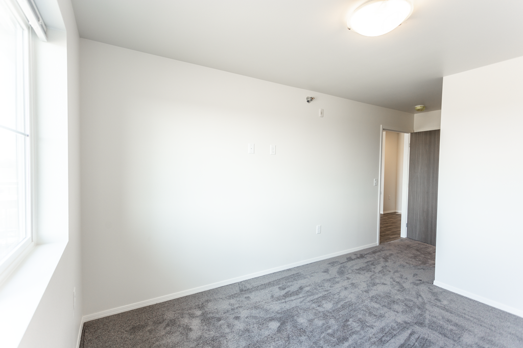 A room with a carpeted floor and a door leading to another room.