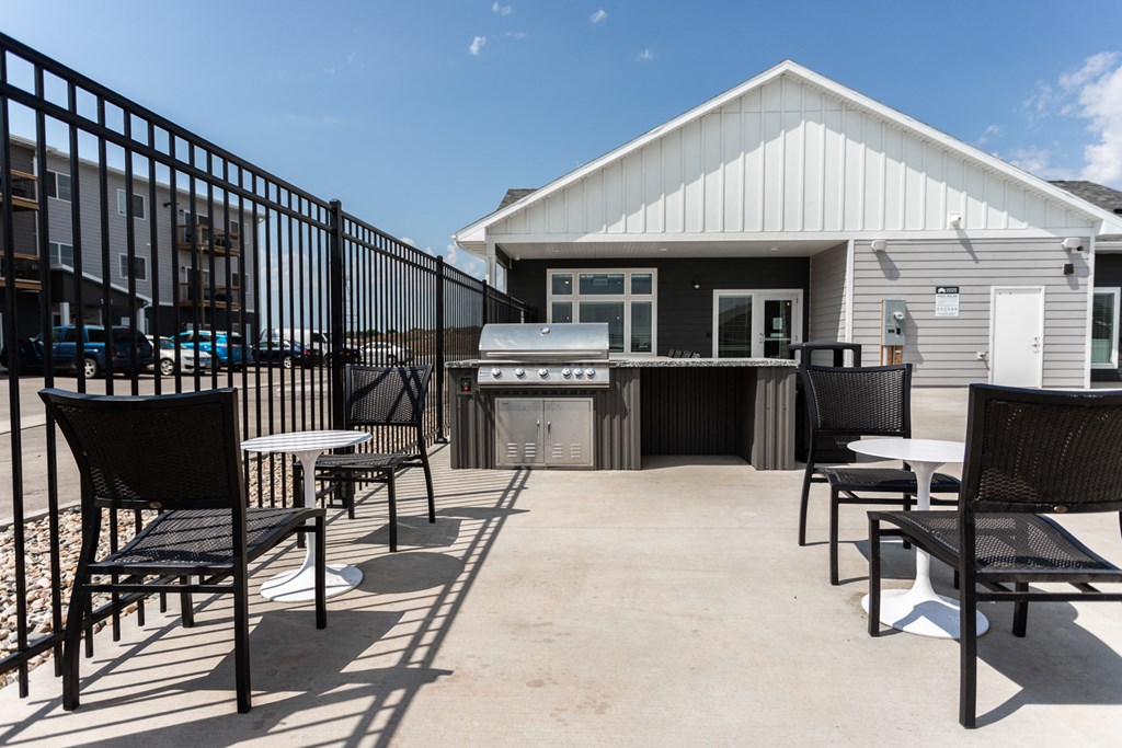 an outdoor patio with tables and chairs and a grill and a building