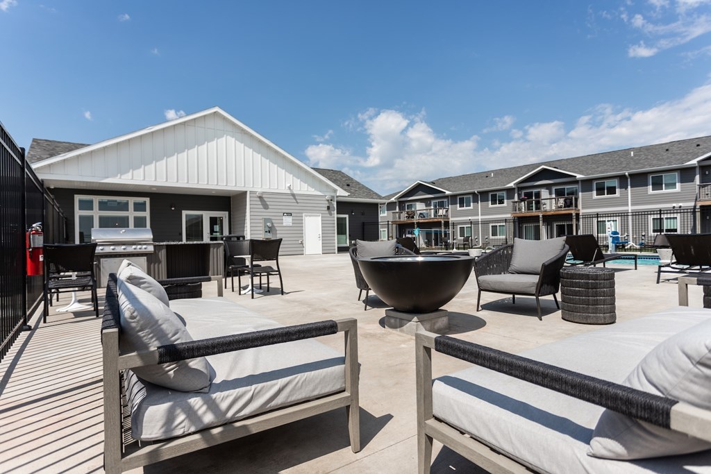 A sunny day at a modern outdoor living space with a fire pit and seating area.