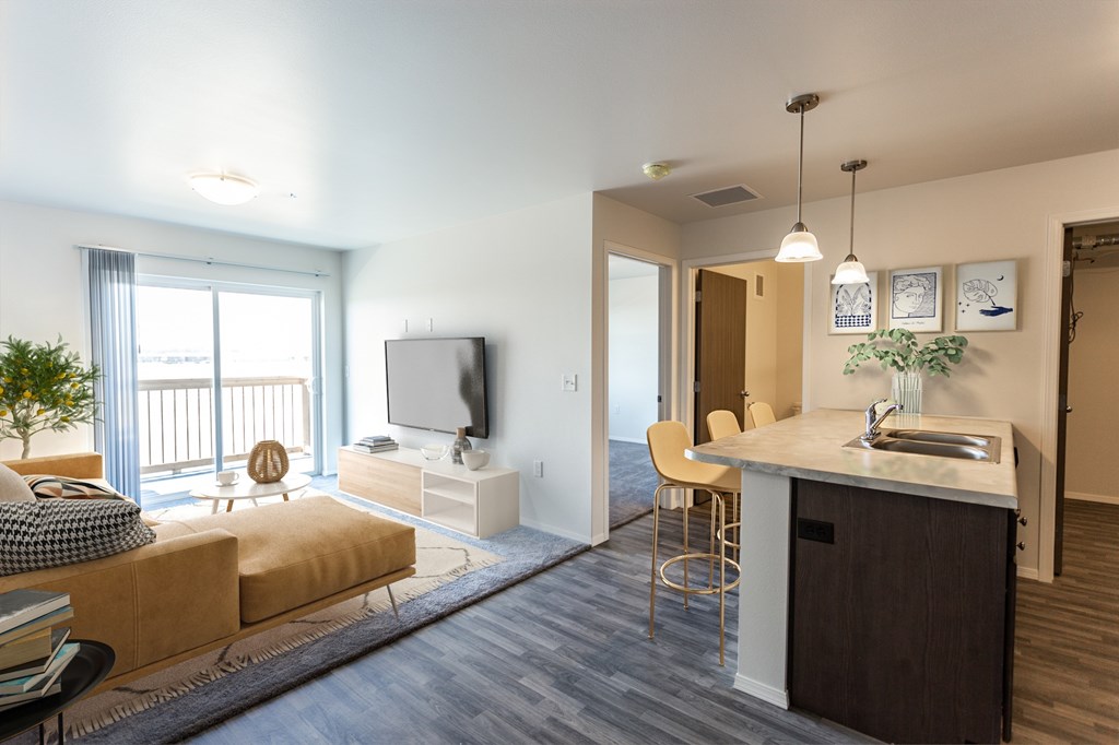 A modern living room with a large window, a sofa, a TV, and a kitchenette.