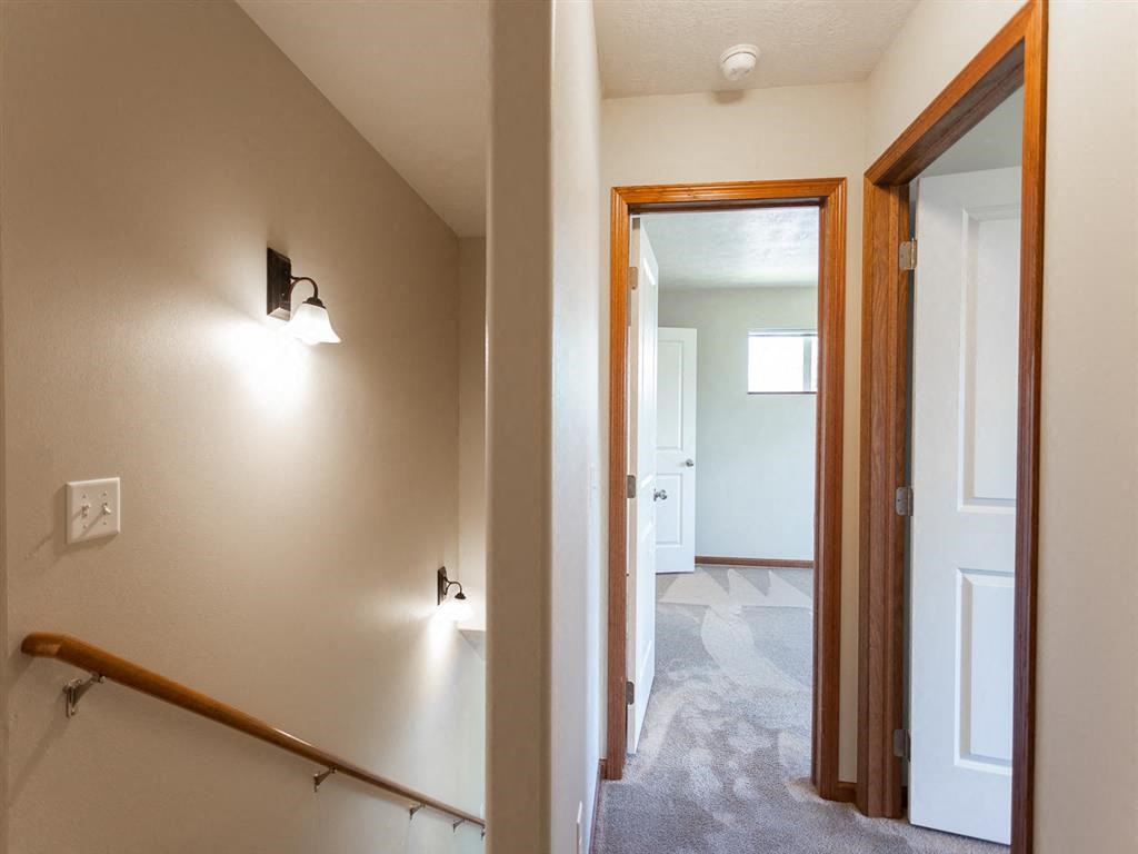 a view of a hallway with a staircase and a door to a bedroom