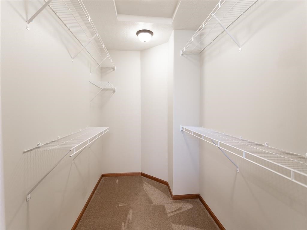 a spacious walk in closet with two mirrored closets
