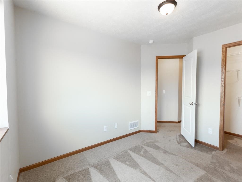 a room with a carpeted floor and a door to a closet