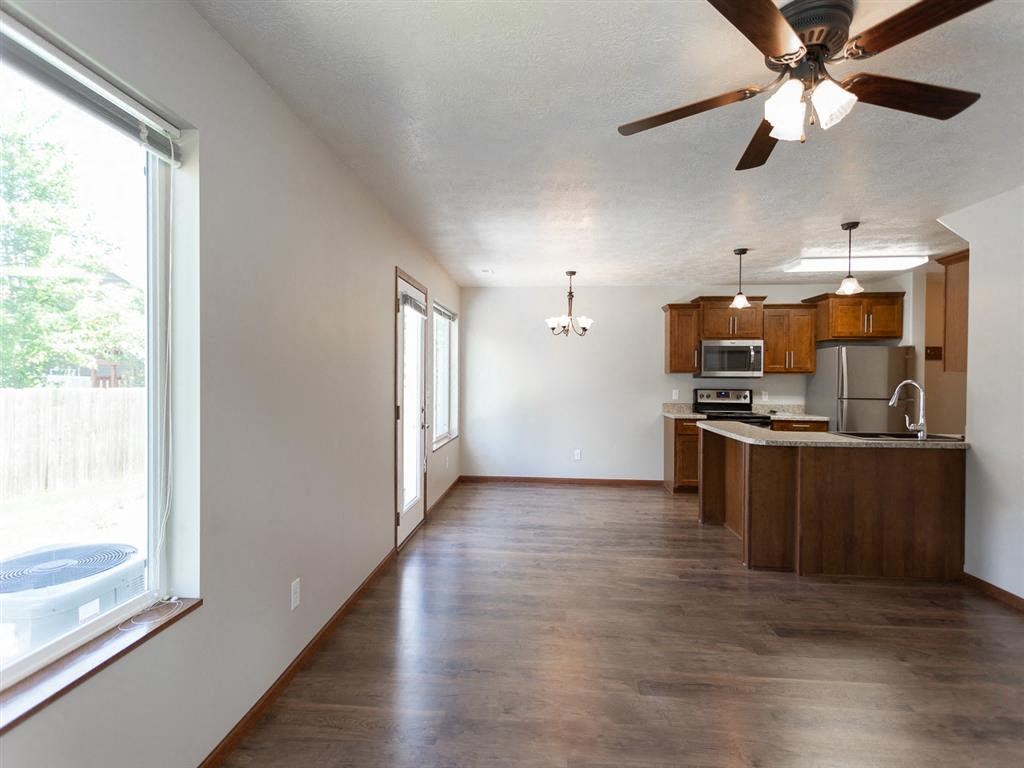 an empty kitchen with a ceiling fan and a large window