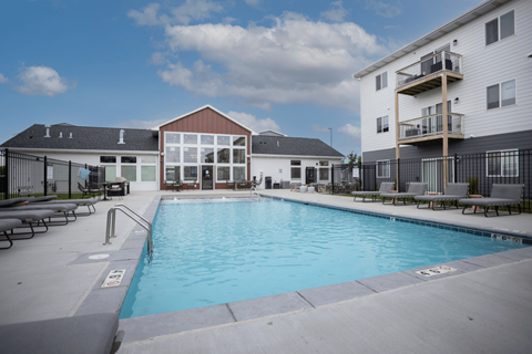 A swimming pool in front of a building with a black fence around it.