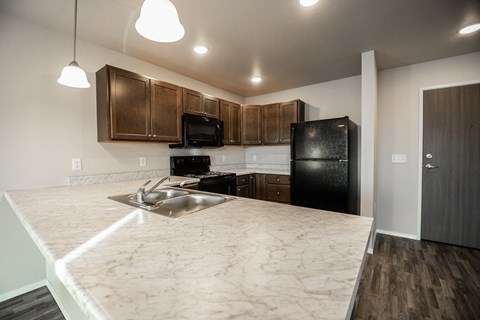a kitchen with a marble counter top and a black refrigerator