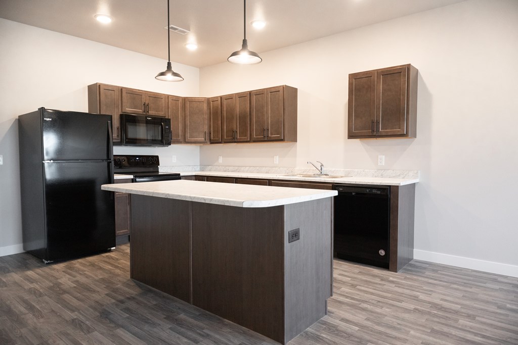 A kitchen with a black refrigerator, microwave, and oven.