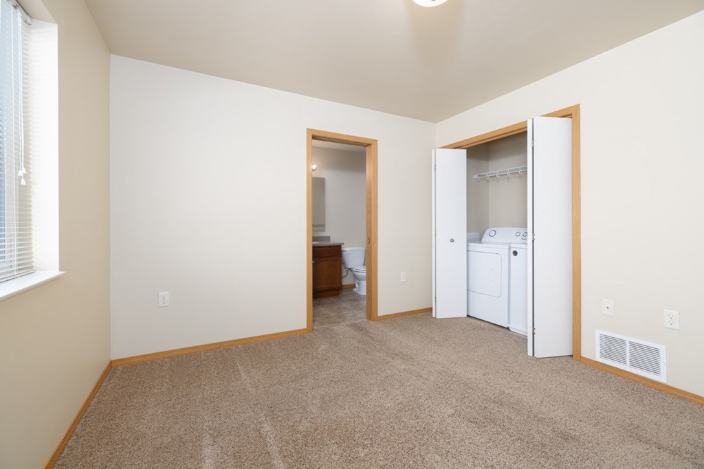 A room with a white fridge and a brown carpet.
