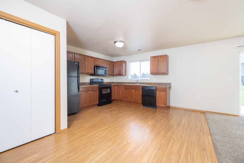 A kitchen with wooden cabinets and a black fridge.
