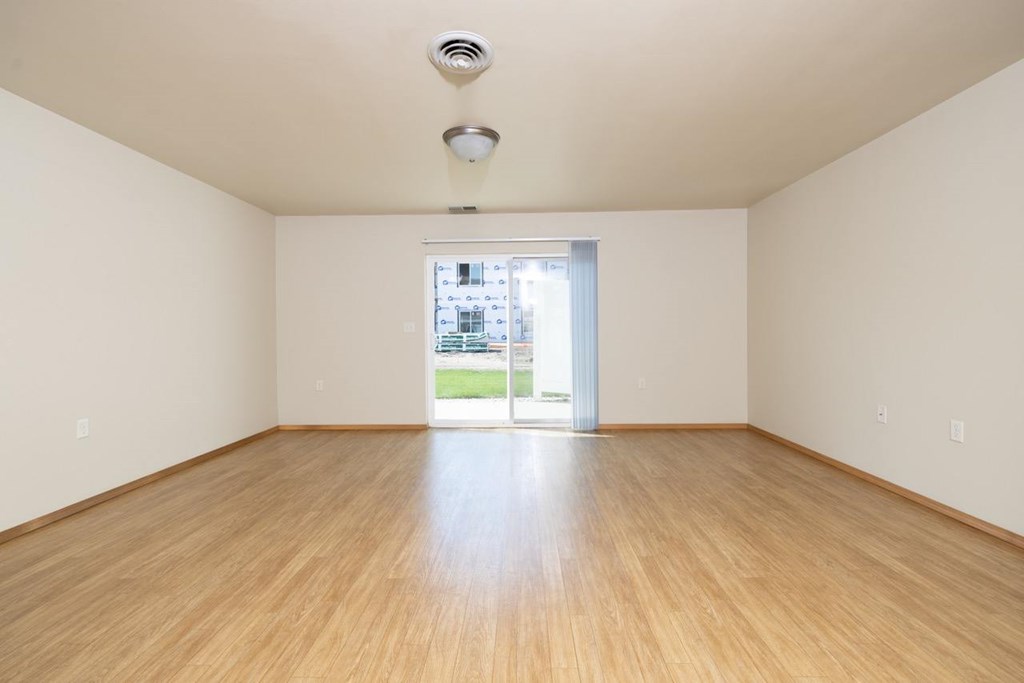 A room with wooden floors and a window showing a street view.
