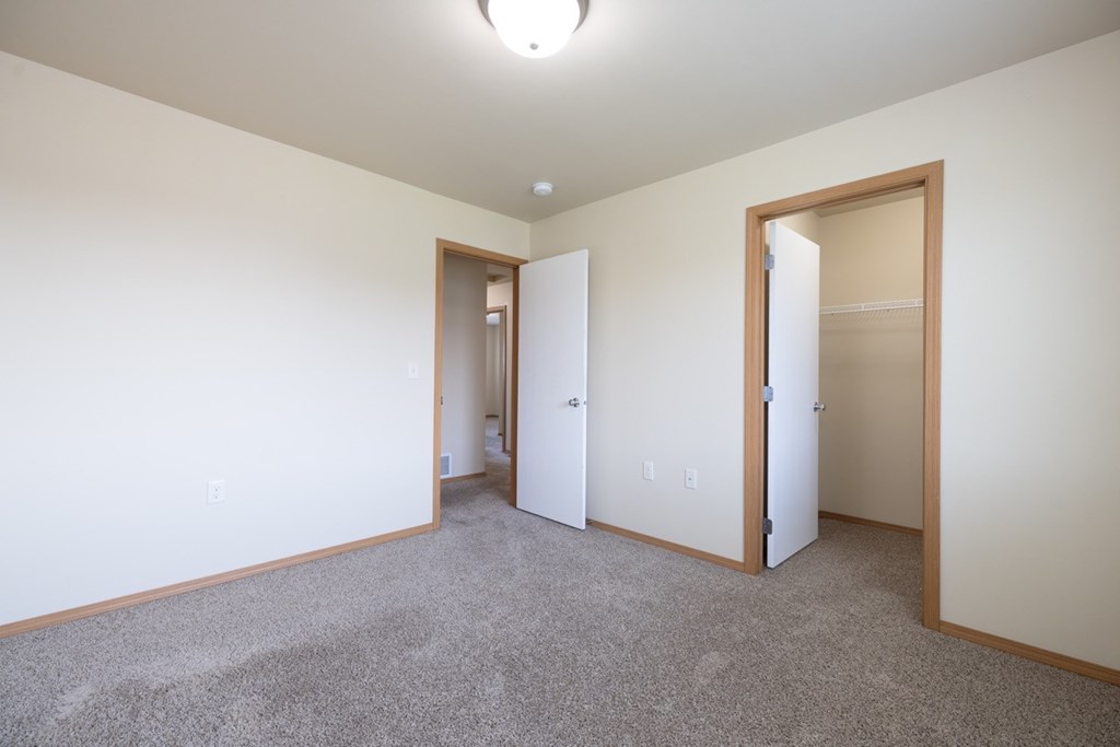 A room with a carpeted floor and two open doors.